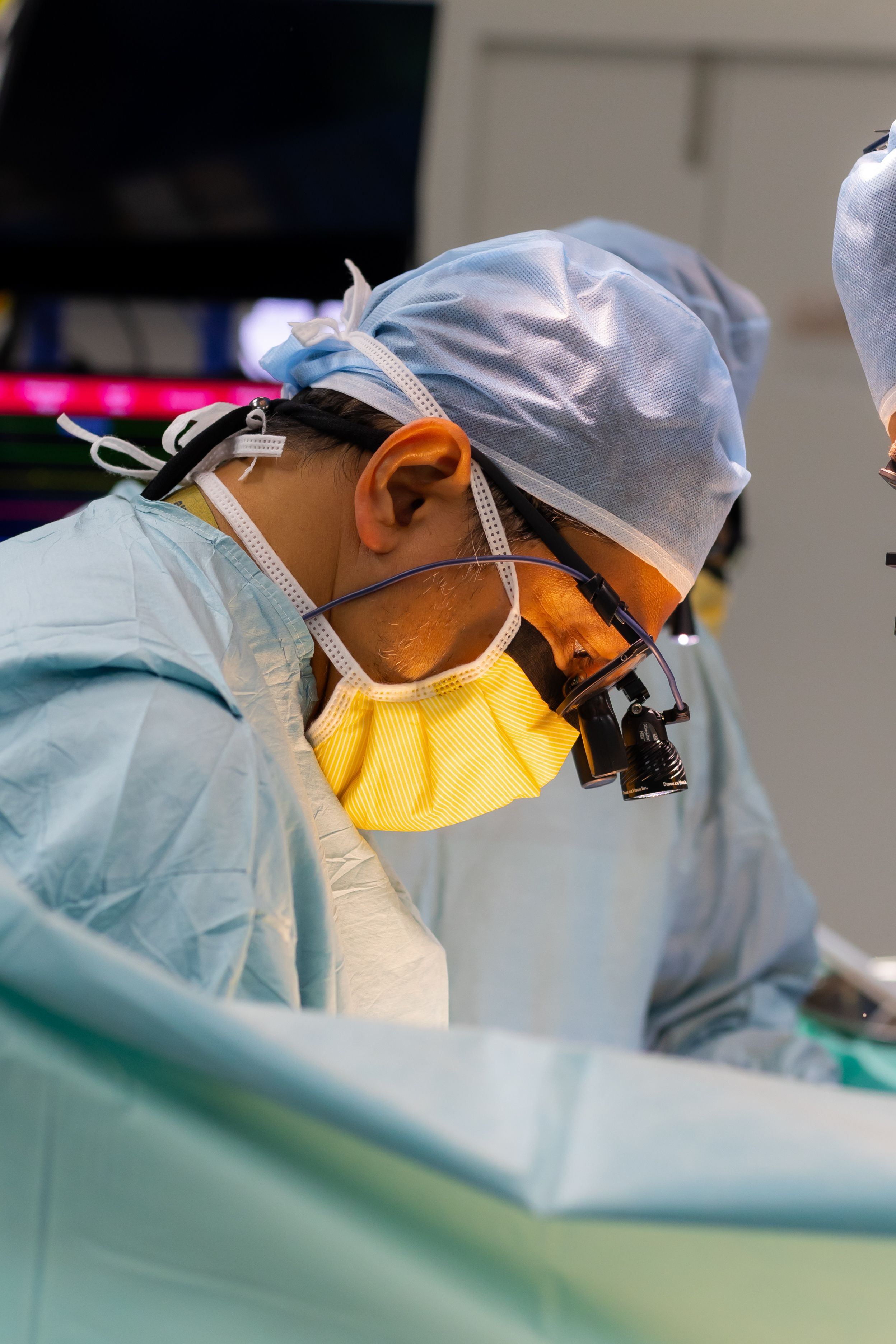 Prof. Dr. Shahrul Amry Hashim in close concentration during minimally invasive cardiac surgery at KPJ DSH2, wearing surgical loupes