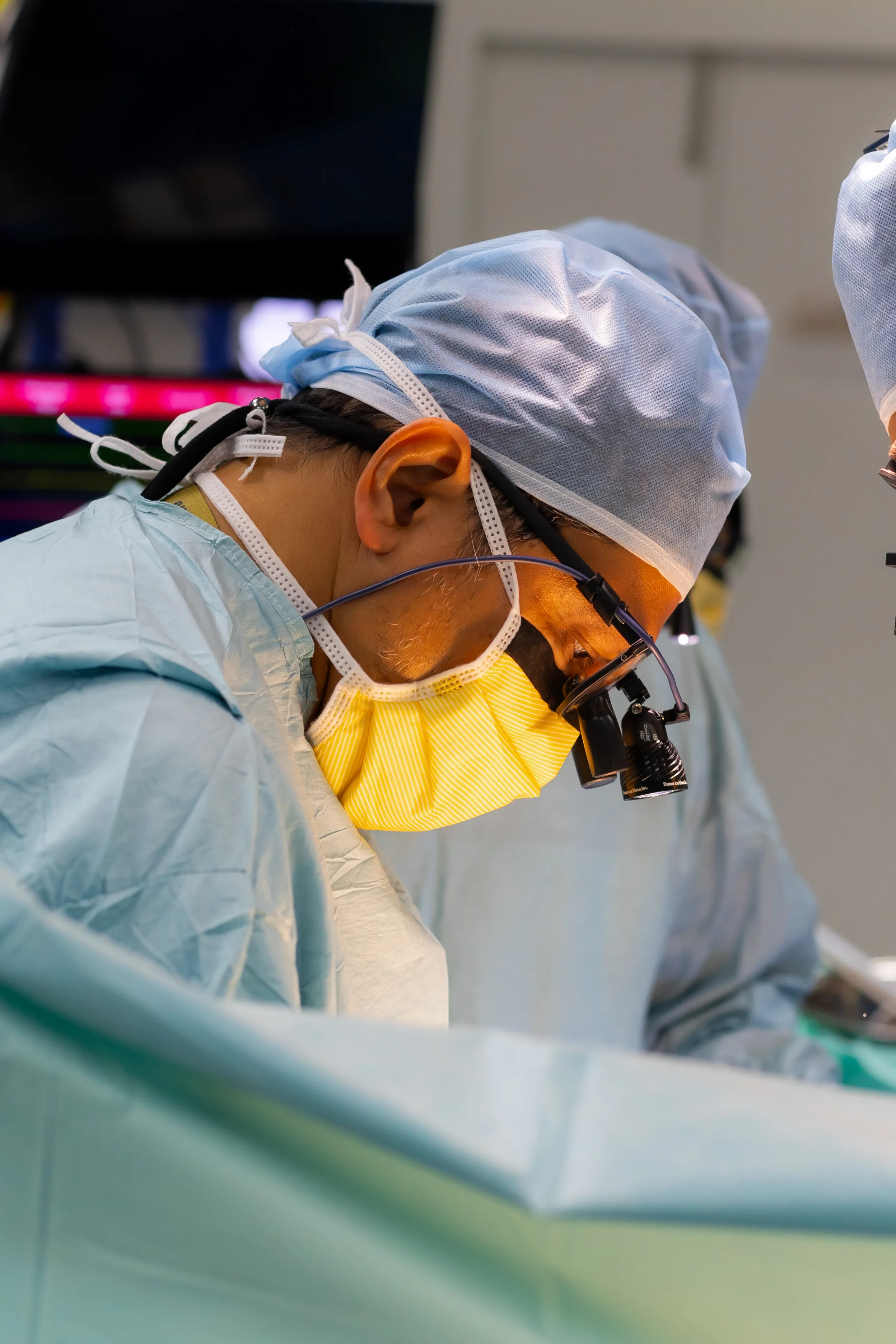 Prof. Dr. Shahrul Amry Hashim in close concentration during minimally invasive cardiac surgery at KPJ DSH2, wearing surgical loupes