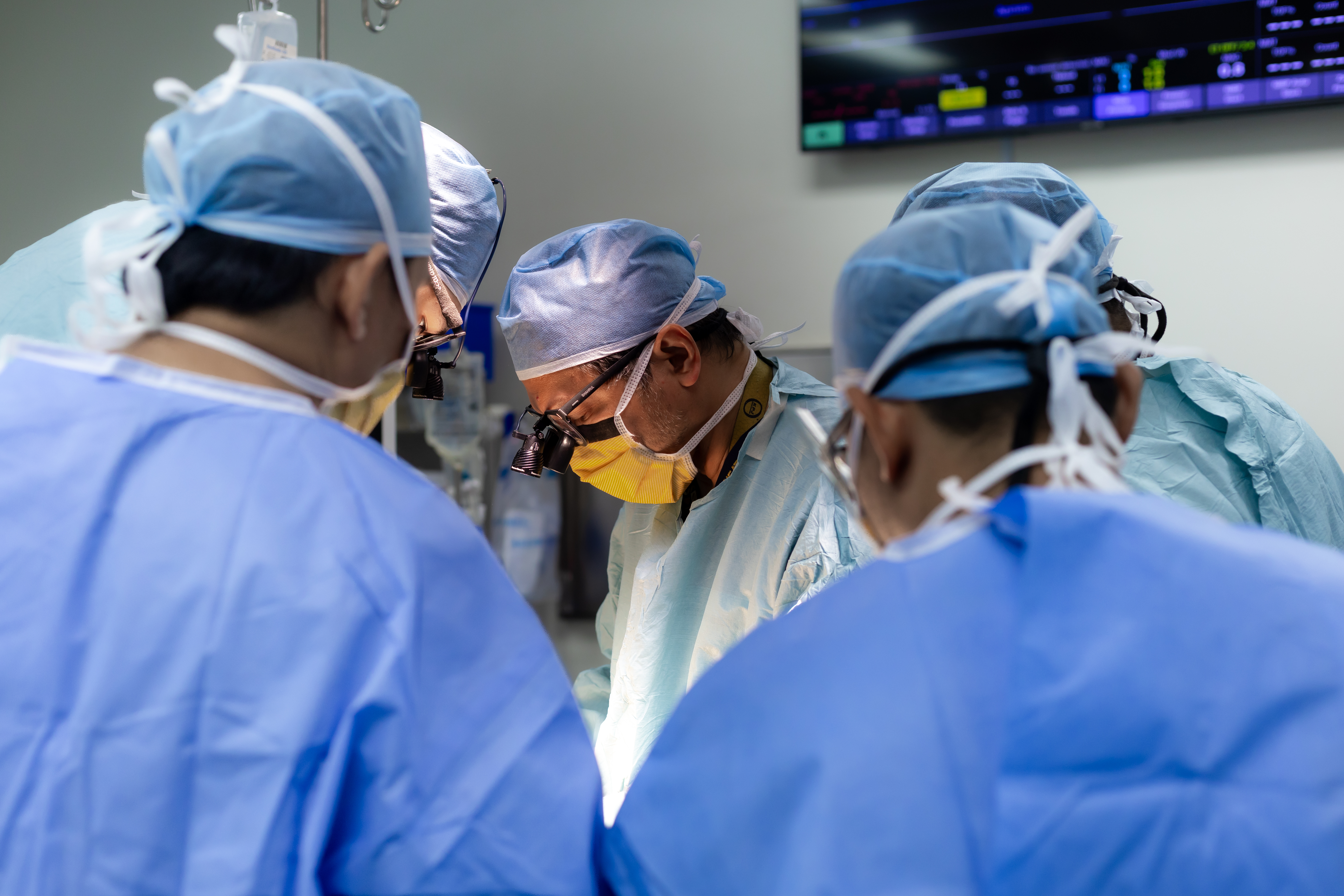 Prof. Dr. Shahrul Amry Hashim and his surgical team performing a minimally invasive cardiac procedure at KPJ DSH2, with cardiac monitoring equipment visible in the background